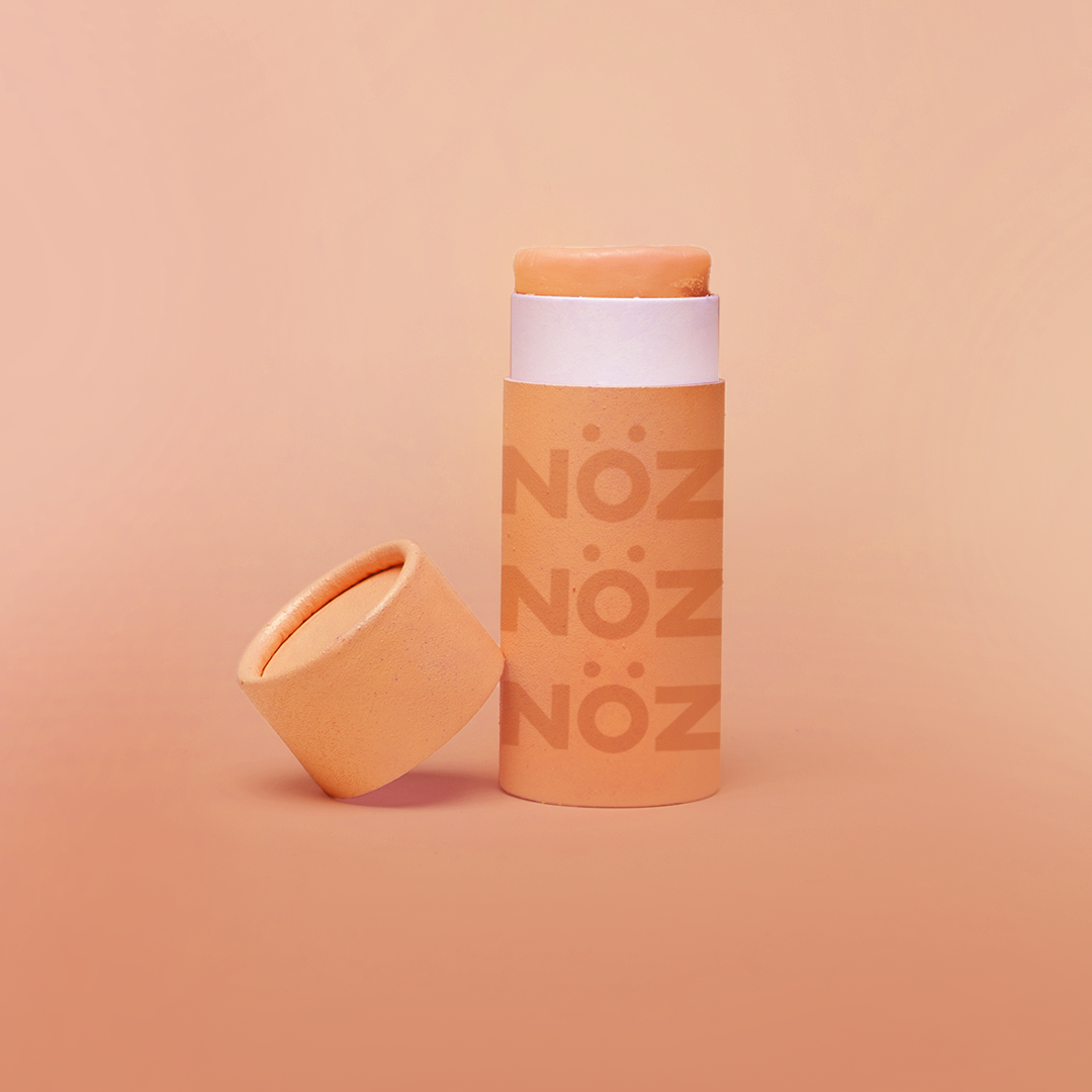 Nöz reef safe sunscreen shown in orange with cap off to show product texture.