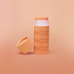 Nöz reef safe sunscreen shown in orange with cap off to show product texture.