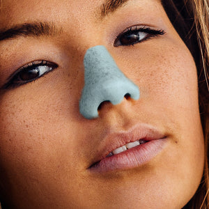 Female model wearing Nöz reef safe sunscreen in blue. 